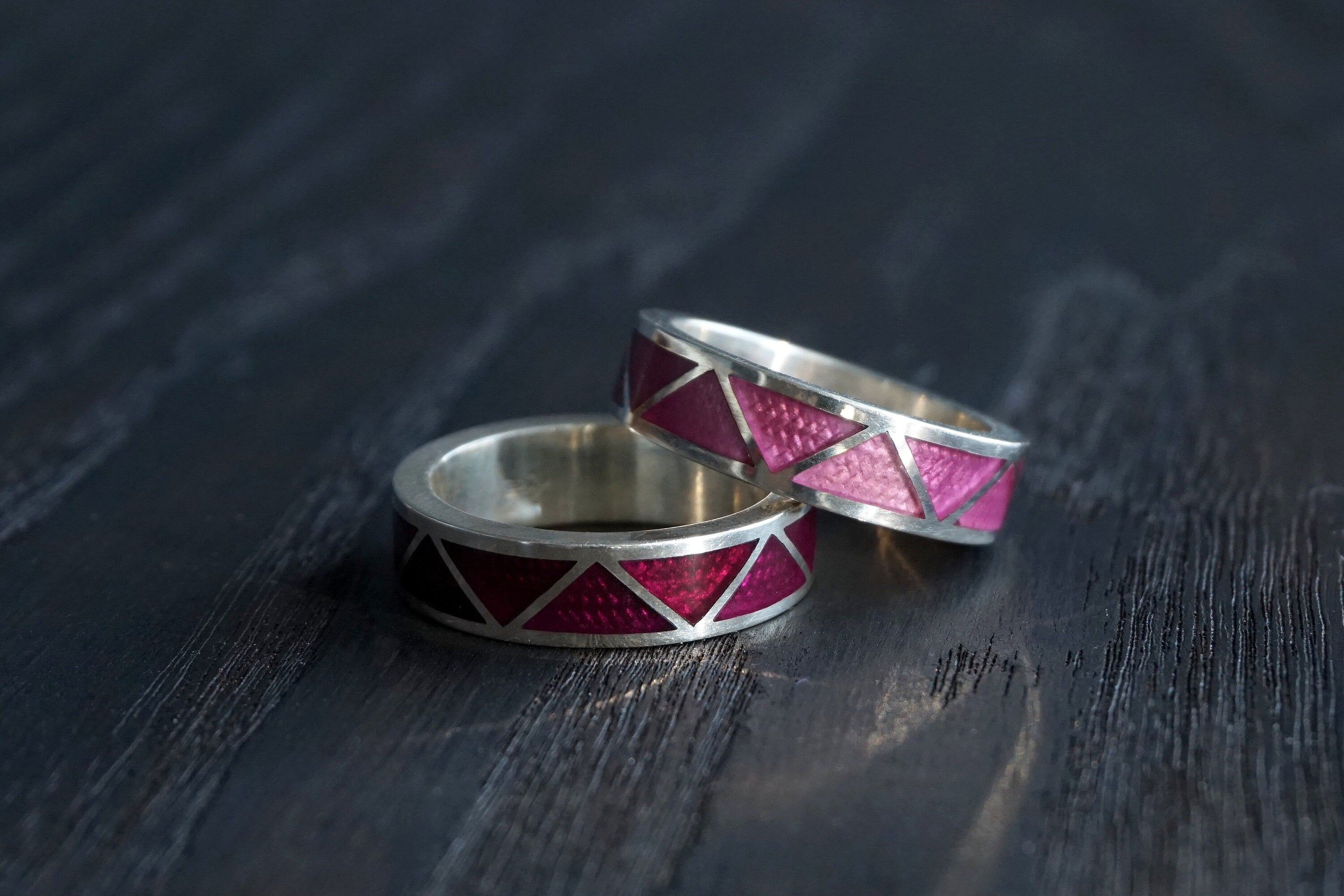 Two silver rings with red and pink geometric patterns