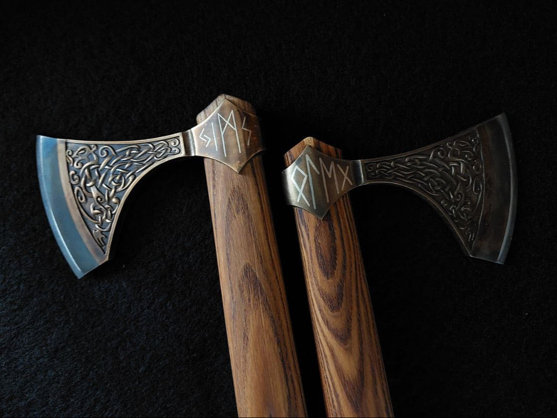 Two axes with wooden handles and metal heads on a dark background