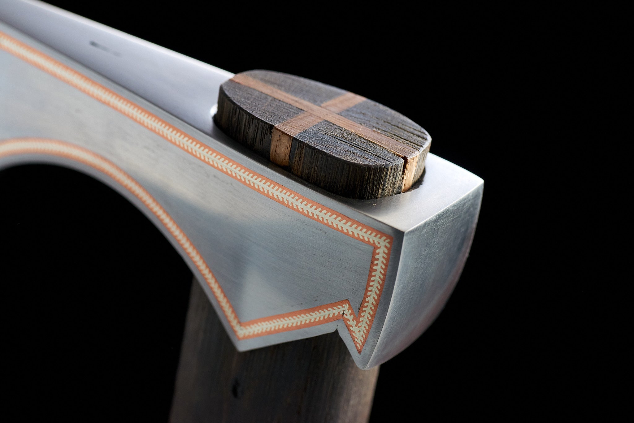 Close-up of copper and silver inlay craftsmanship on collectible axe