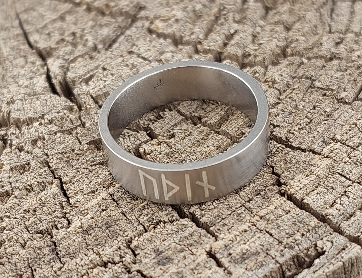 Minimalist Viking titanium ring with silver rune inlay standing at an angle, handcrafted satin matte finish inspired by Norse jewelry.