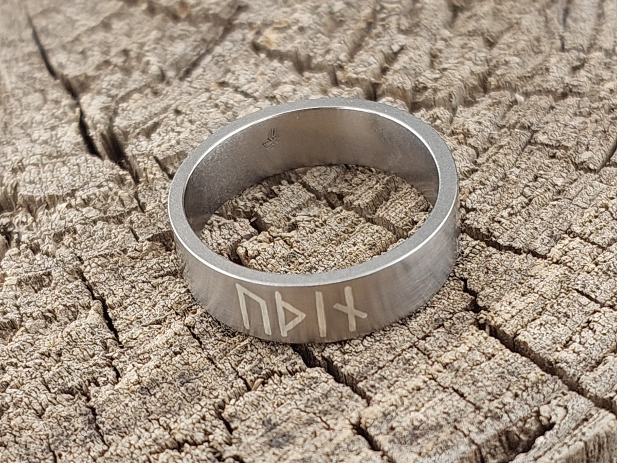 Minimalist Viking titanium ring with silver rune inlay standing at an angle, handcrafted satin matte finish inspired by Norse jewelry.
