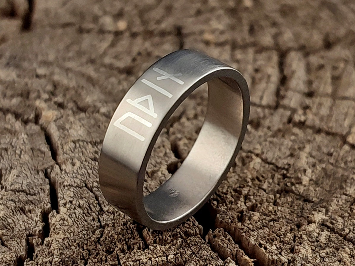 Close-up detail of handcrafted titanium Viking ring with authentic Younger Futhark Odin inscription and silver metal inlay.