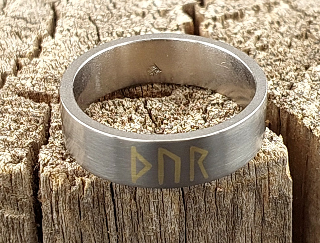 Minimalist Viking titanium ring with Thor rune brass inlay standing at an angle, handcrafted matte brushed Nordic band.
