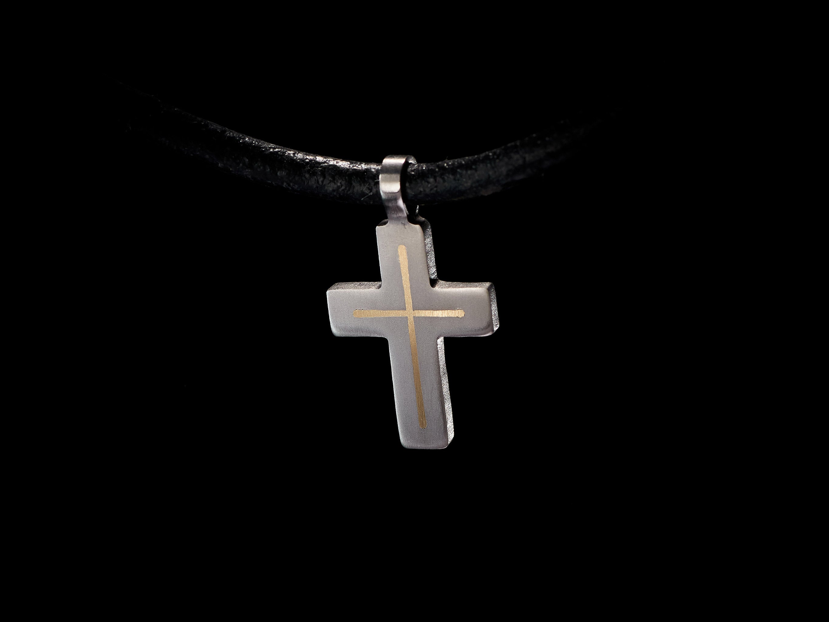 Close detail view of handmade titanium cross pendant with brass inlay