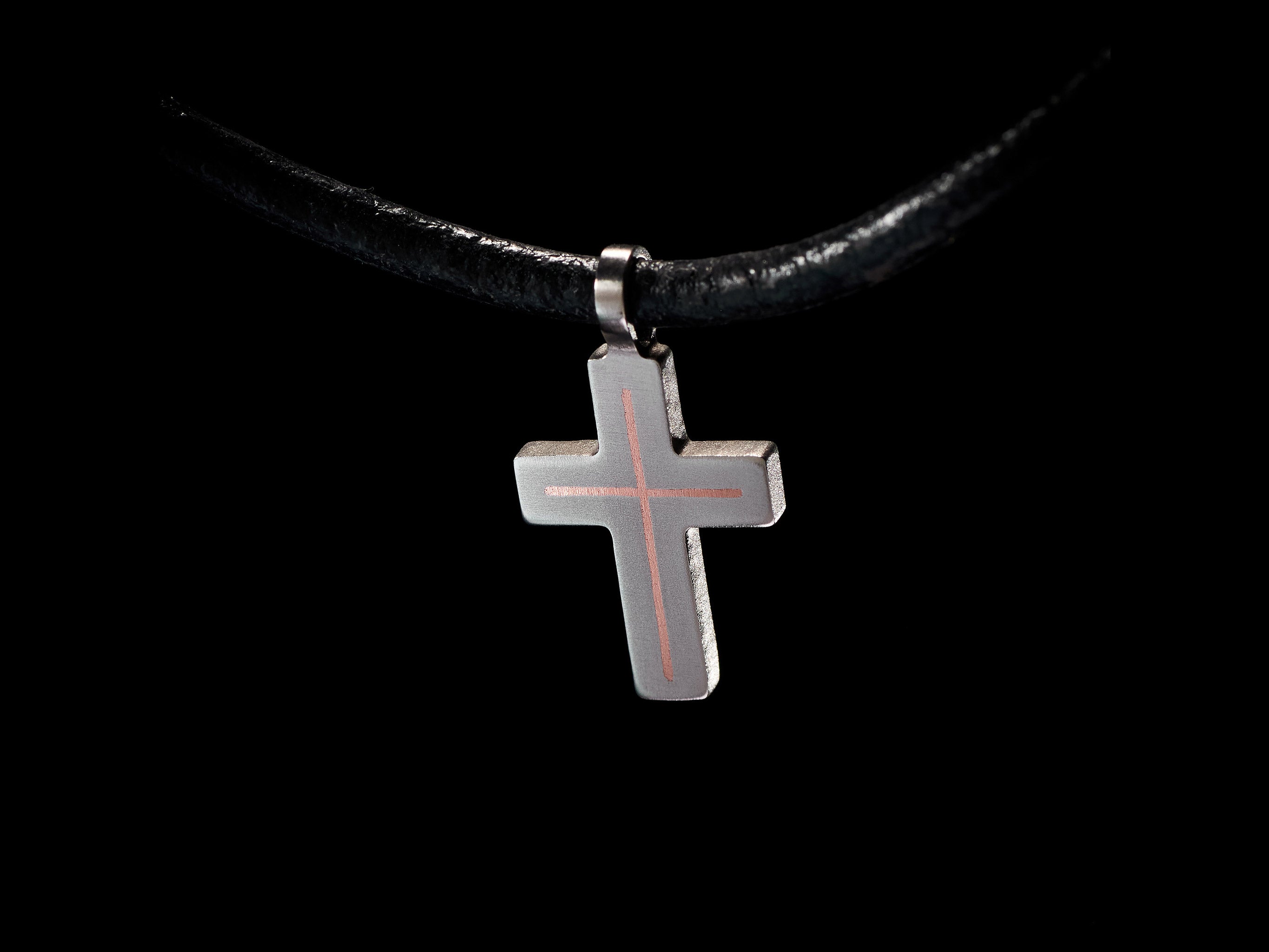 Close detail view of handmade titanium cross pendant with copper inlay