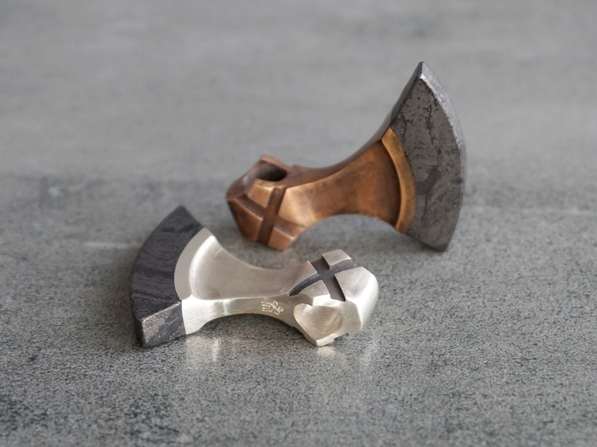 silver and bronze axes with grey stone blade