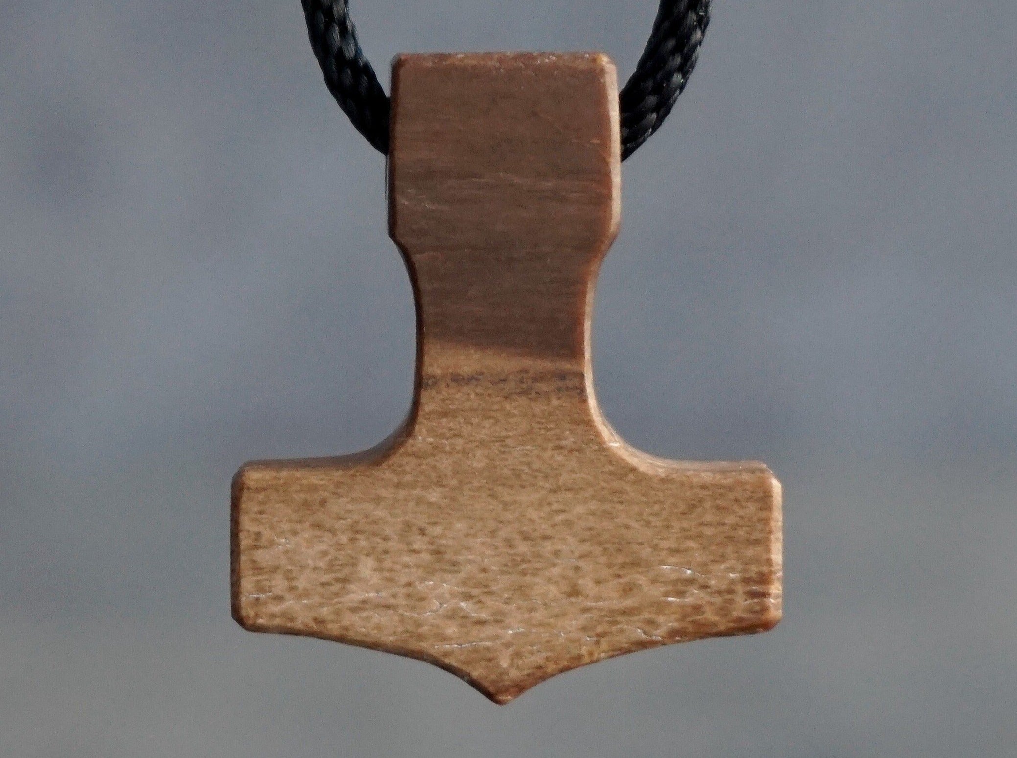 small Thor's hammer carved out of petrified wood: dark top, light bottom