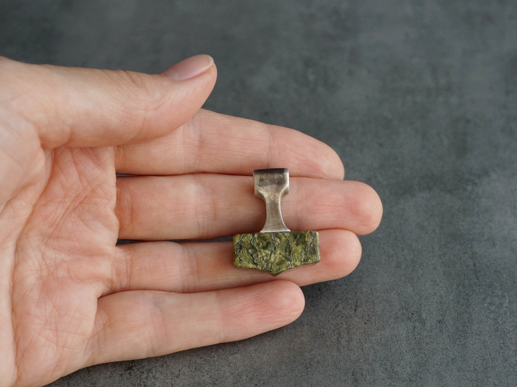 small hammer pendant made of silver and green stone