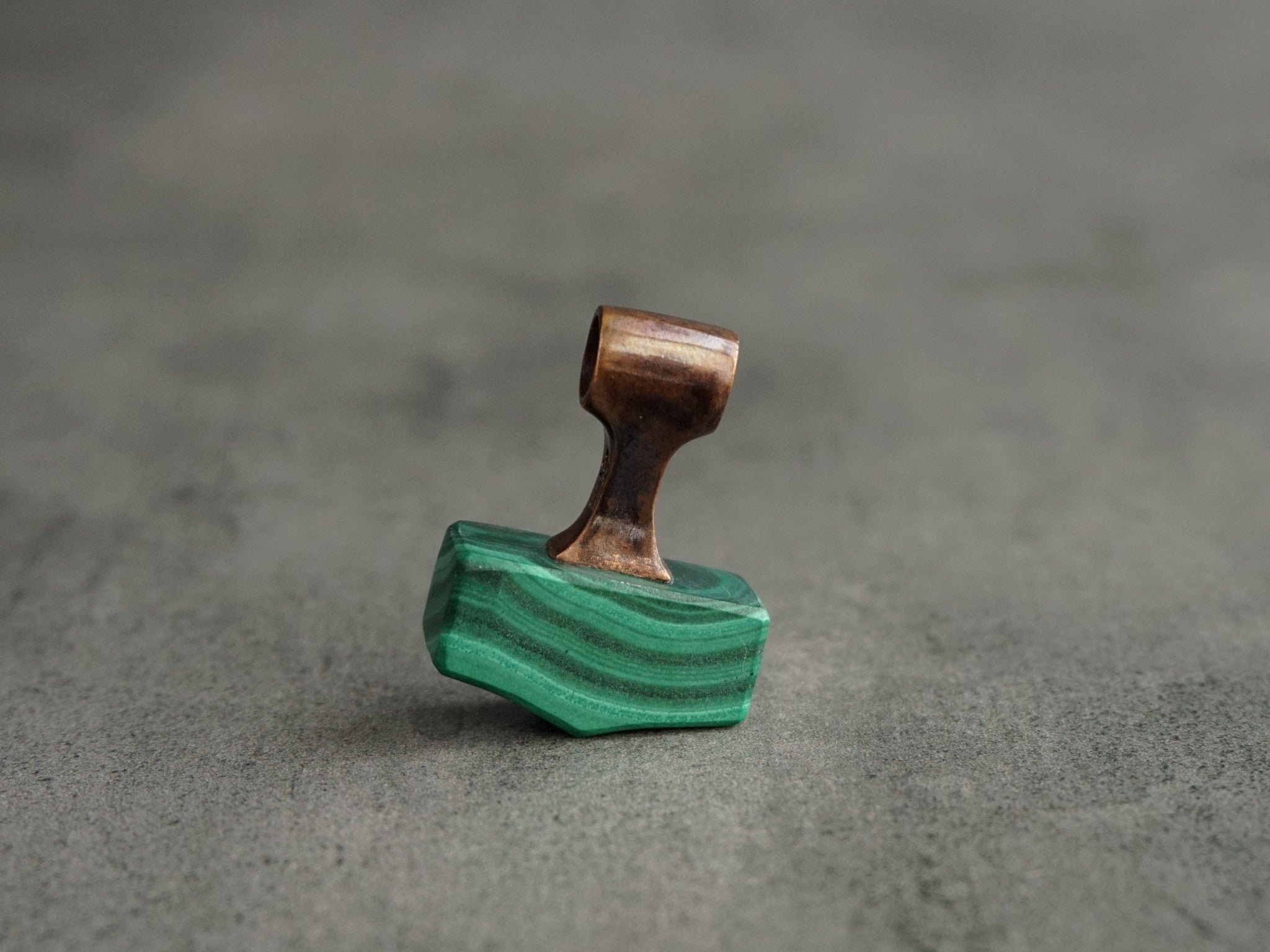 small bronze pendant with wavelike patterns in the green stone