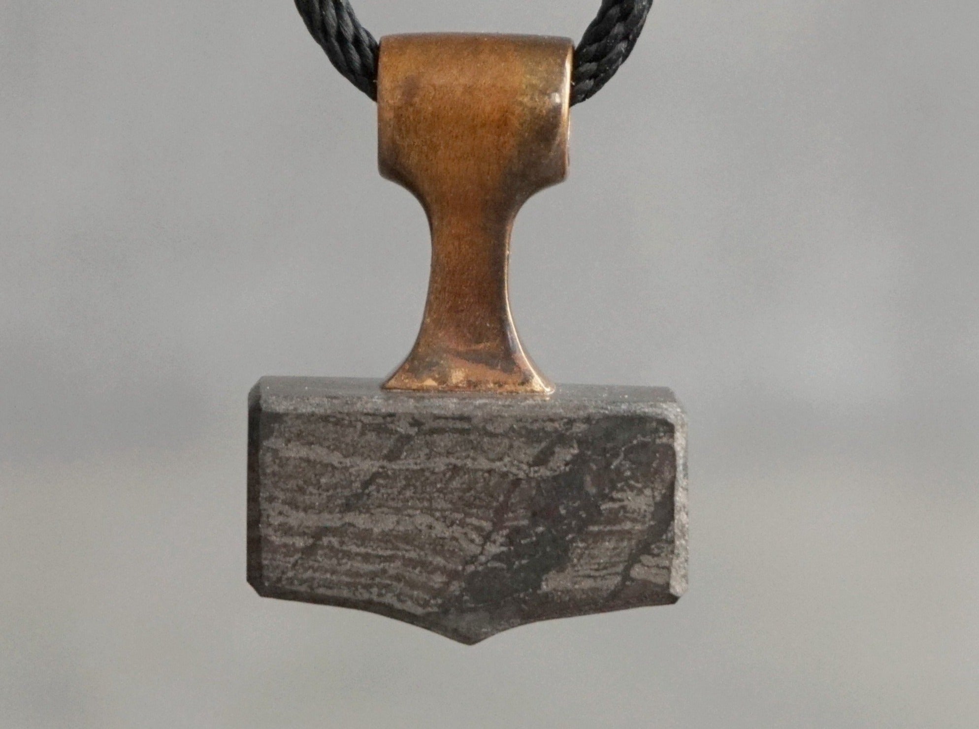 small hammer pendant made of bronze and grey stone
