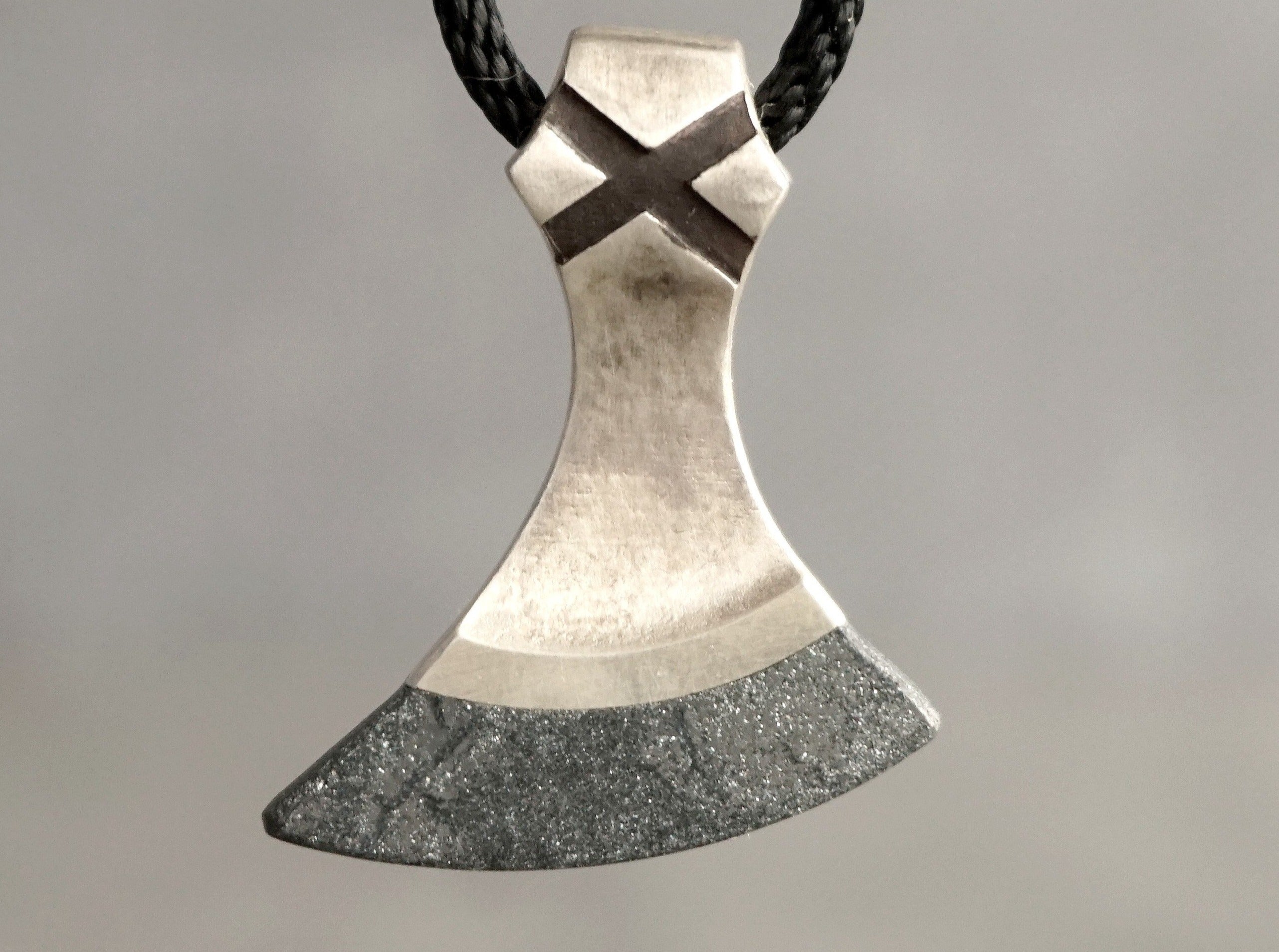 handmade axe necklace made of silver and specular hematite hanging on a cord necklace