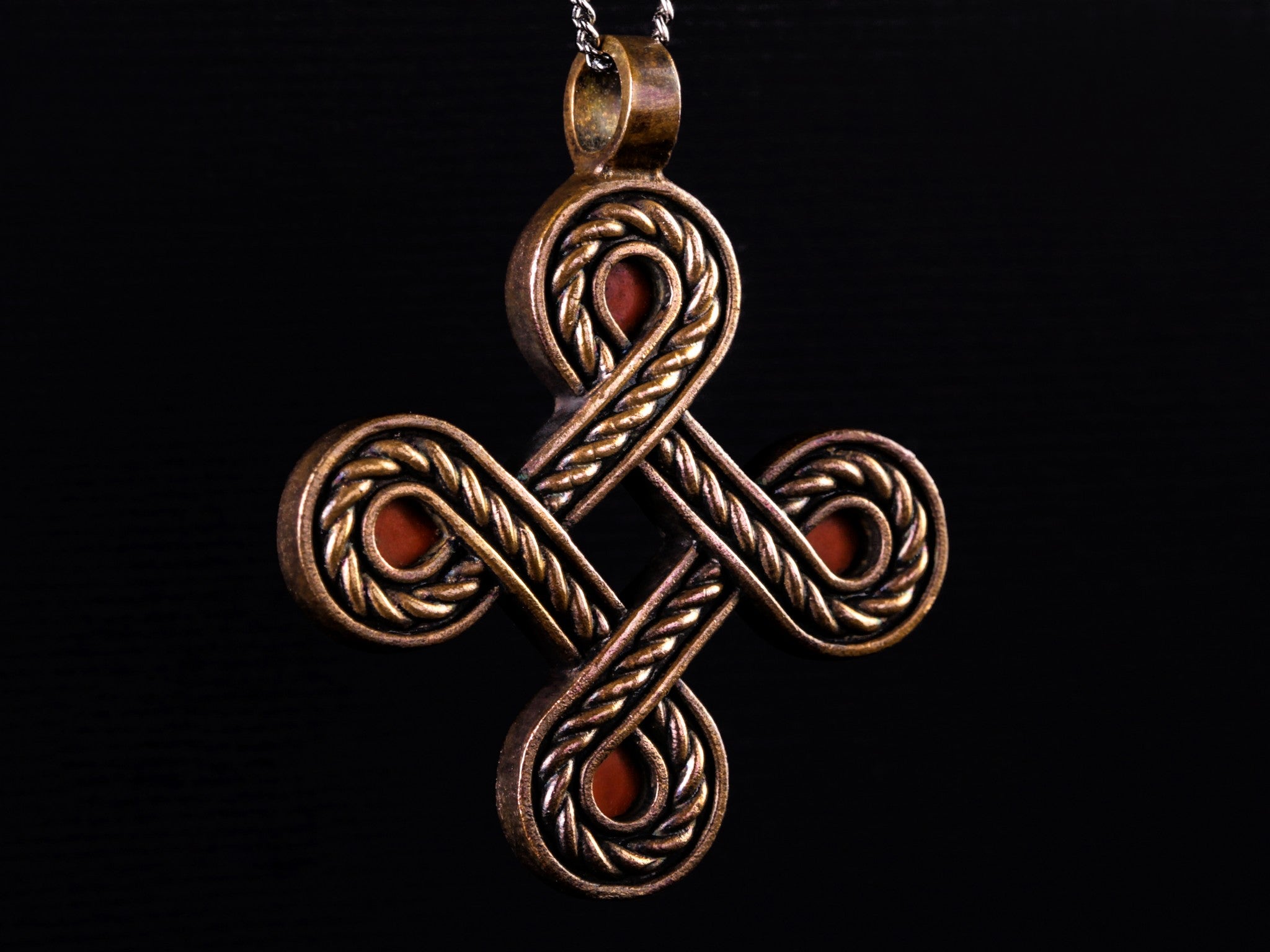 large rope-like bronze cross with red stones