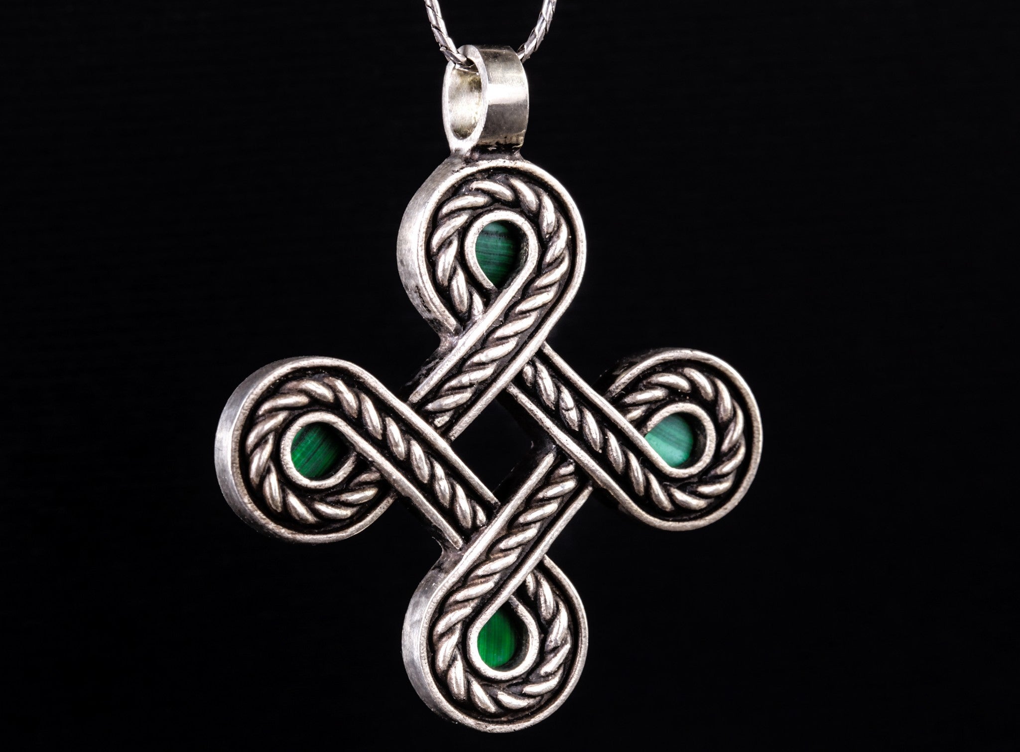 large rope-like silver cross with green stones